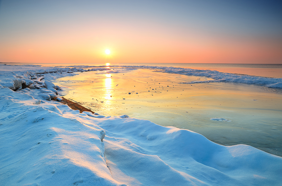 colorful sunset at the snowy baltic sea shore